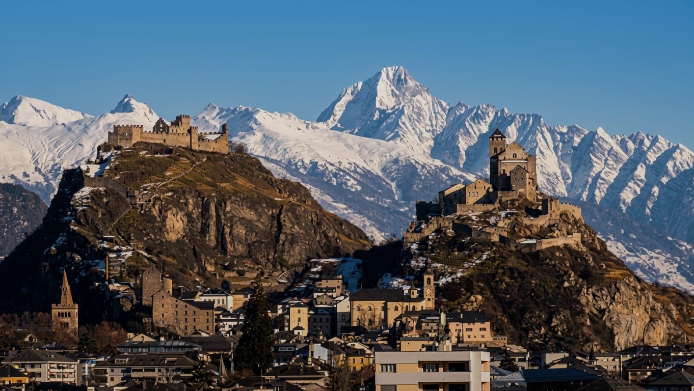 Les collines de Valère et de Tourbillon à Sion en hiver, vues depuis l’ouest, avec les montagnes enneigées derrière
